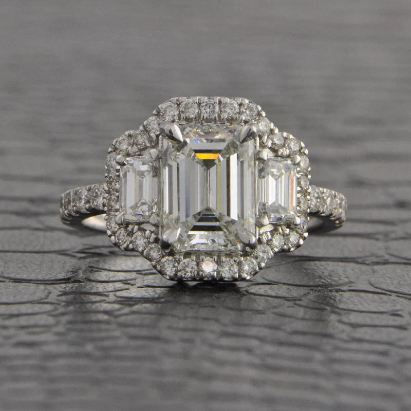 Magnificent Three Stone Emerald Cut Halo Engagement Ring in White Gold